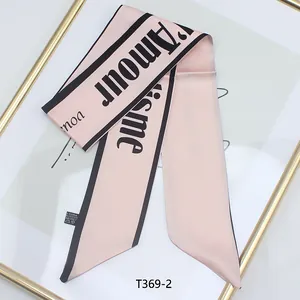 Détail d'un foulard en satin rose avec lettrage L'Amour noir et pointe élégante