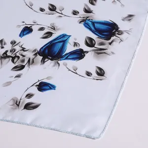 Detailed macro view of blue rose pattern and satin finish on a white silk scarf