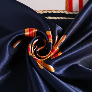 Carré de soie marine et orange à motif cordage nautique présenté en spirale élégante
