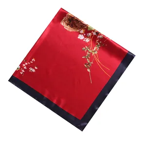 Detailed close-up of glossy red silk scarf with peony patterns and navy blue borders