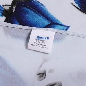 Close-up of a blue rose silk scarf featuring exquisite rolled edges and fabric care label