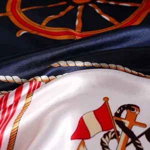 Détail d'un foulard en soie montrant des motifs nautiques brillants et des ancres