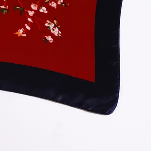 Detail of red silk square scarf with floral pattern and dark navy satin border edges
