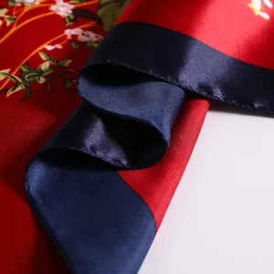 Close-up of red rose floral silk scarf with glossy satin texture and navy blue border