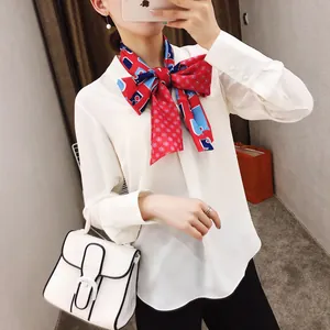 Detail van een witte zijden blouse met een rood en blauw geruit zijden halssnoer