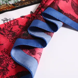 Macro shot of red floral silk scarf featuring black butterflies and blue hem detail