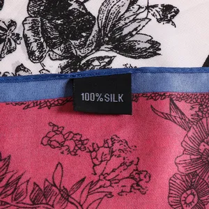 Detailed close-up of 100% silk twill scarf showing floral pattern and blue hemmed edge