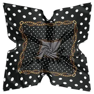 Close-up of square silk scarf featuring black polka dots and golden chain patterns