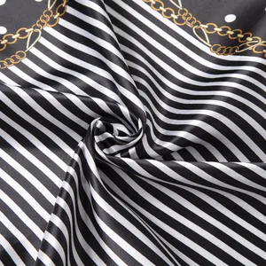 Macro shot of satin silk scarf featuring black white stripes and gold chain patterns