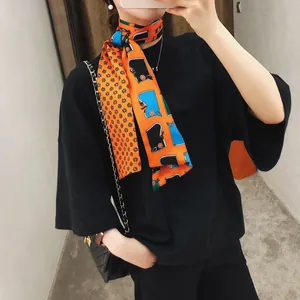Detail van een oranje zijden sjaal met ruiterspatronen gedragen op een zwart shirt