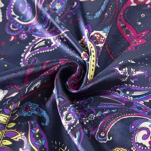 Macro detail of silk-satin paisley pattern scarf with vibrant swirls on navy blue fabric
