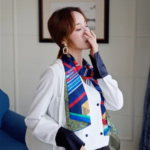 Close-up of geometric striped silk scarf styled with a white blazer on a model