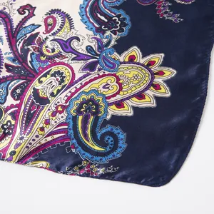 Detailed close-up of colorful paisley pattern on dark blue silk-like square scarf fabric