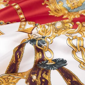 Détail macro de chaîne fer à cheval royale et glands dorés sur foulard en soie rouge