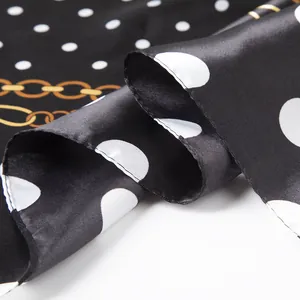 Detail of silk-like satin scarf featuring white polka dots and gold chain patterns