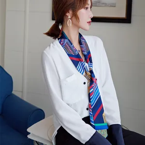 Detail of a geometric striped twilly silk scarf tied elegantly on a white shirt collar