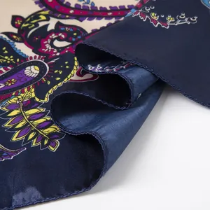 Macro view of blue paisley patterned satin silk scarf featuring premium hemmed edges