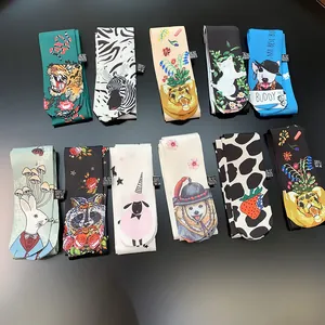 Flat lay of 11 assorted cartoon animal print silk scarves for handbags on black background