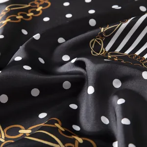 Macro shot of silk scarf fabric featuring white polka dots and golden chain patterns