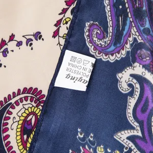 Macro detail of navy blue paisley silk scarf fabric texture and polyester care label