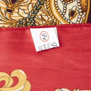 Détail de la couture du foulard en soie et étiquette d'entretien sur tissu satiné rouge