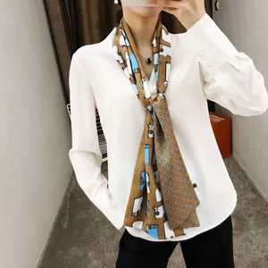 Detail van de geruite zijden sjaal gedragen op een witte blouse en zwarte outfit voor dames