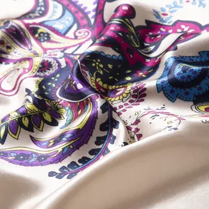 Close-up of elegant champagne paisley silk scarf showing satin texture and vibrant patterns