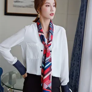 Detail of geometric pattern twill silk scarf draped on a white shirt with navy cuffs