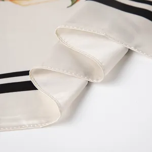 Close-up of smooth satin silk scarf with black striped edges and calla lily prints