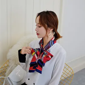 Detail of multi-color geometric silk scarf tied in a bow on a white satin shirt