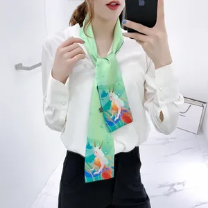 Dettaglio di un foulard di seta verde chiaro con stampa a sirena su camicia bianca