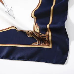 Detailed view of nautical silk scarf featuring navy blue edges and golden emblem patterns