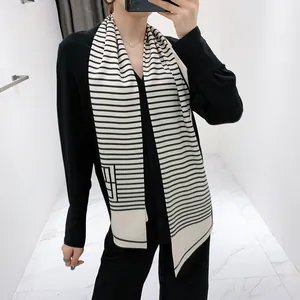 Detailopname van een zwart-witte gestreepte zijden sjaal gestyled op zwarte kleding