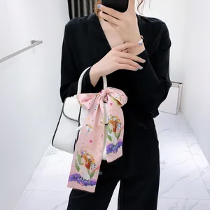 Dettaglio di un foulard in seta rosa Vergine annodato su borsa in pelle bianca