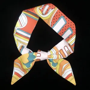 Dettaglio ravvicinato di una sciarpa sottile in seta con stampe geometriche arancioni e blu