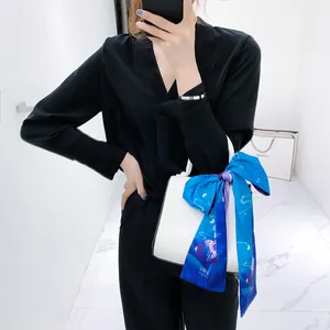 Dettaglio di una borsa bianca decorata con nastro di seta blu e costellazione dello Scorpione