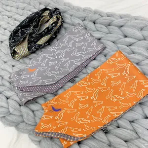 Detail of bird print double-layer silk scarves in black, grey and orange on a knit texture