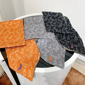 Close-up of bird pattern twill silk scarves in orange, grey, and black colors