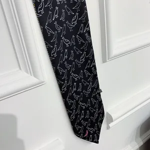 Detail of black silk scarf with bird pattern and a pink accent on white background