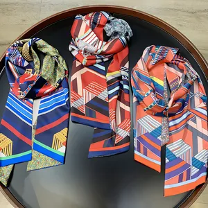 Close-up of geometric pattern silk scarves in navy, red, and orange in a tray