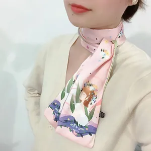 Dettaglio di un foulard di seta rosa con illustrazione floreale portato al collo