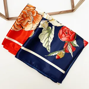 Detail of floral silk scarf with orange lilies on a navy base and white striped borders