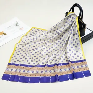 Dettaglio di un foulard in raso di seta con stelle geometriche blu su una borsa in pelle