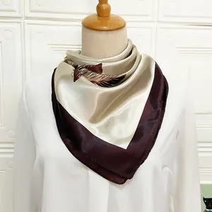 Detail of silk satin square scarf featuring champagne feather prints on a mannequin