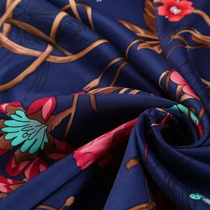 Detail of floral pattern silk scarf with vibrant blossoms on a deep blue fabric background