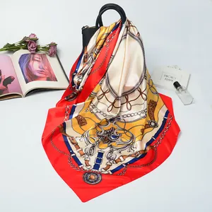 Detail of luxury satin square scarf with belt and chain print draped on a handbag