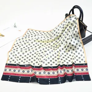 Dettaglio foulard in seta con motivi geometrici neri e bordi colorati su una borsa