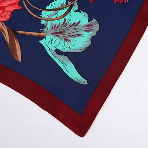 Close-up of silk square scarf featuring detailed floral prints and burgundy borders