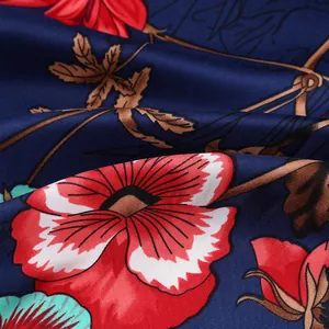 Detail of silk-like twill fabric featuring red flowers and green leaves on dark blue