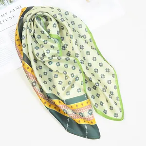 Dettaglio di un foulard in raso con motivi geometrici verdi e arancioni su uno sfondo bianco